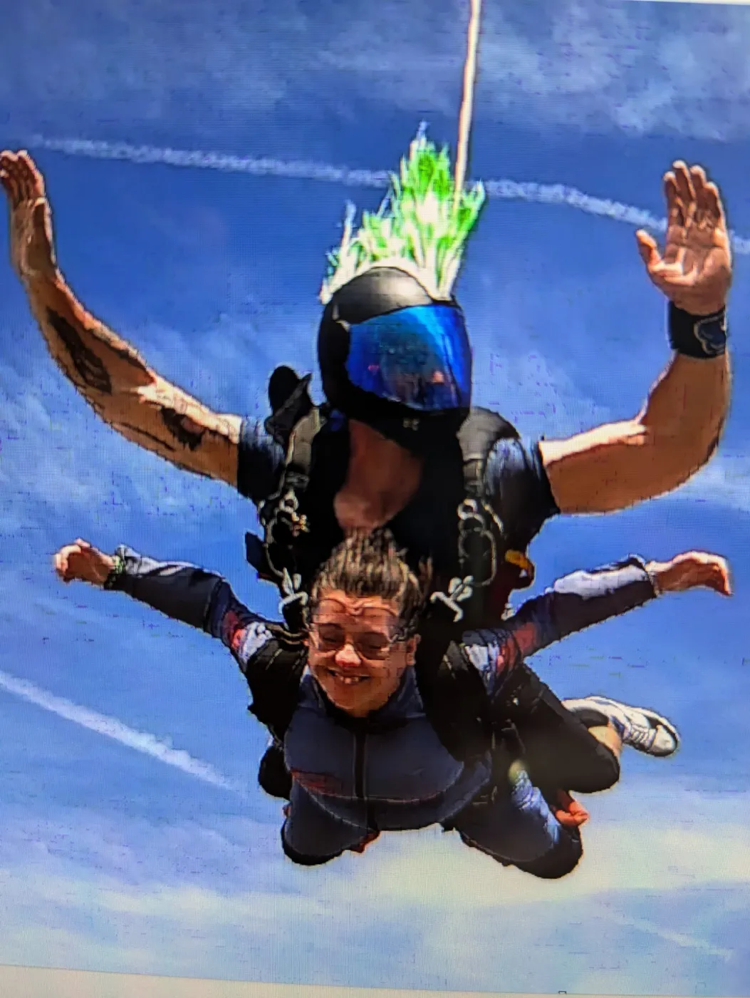 Liz tandem skydiving with her arms out and a huge grin